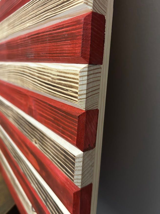 Close-up view of a wooden American flag, with red and natural wood stripes joined at the edges.