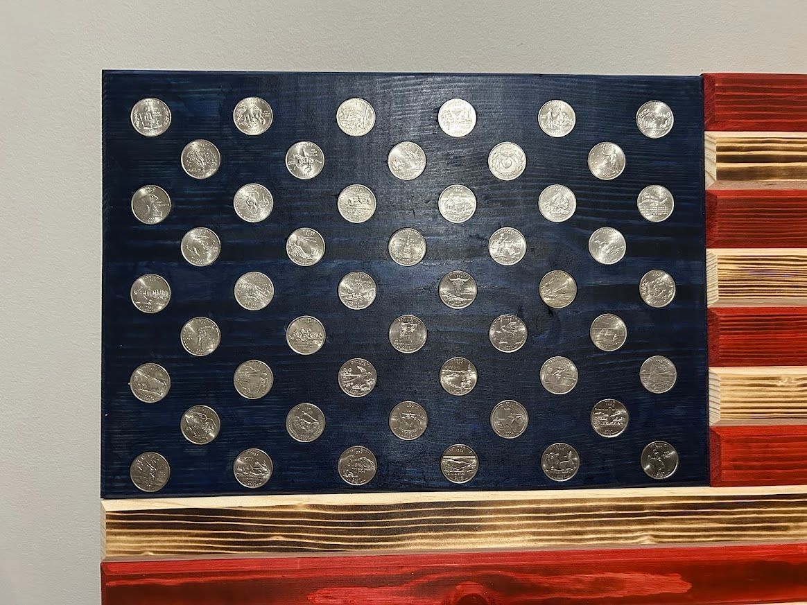 Wooden American flag with silver circle in the blue section and red and white stripes.
