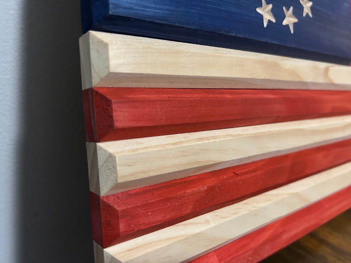 Wooden American flag with blue stars, red and natural wood stripes.