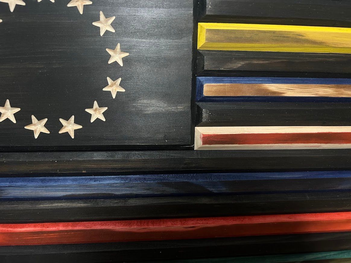 Wooden American flag artwork with colored stripes, and a circle of stars on a black field.