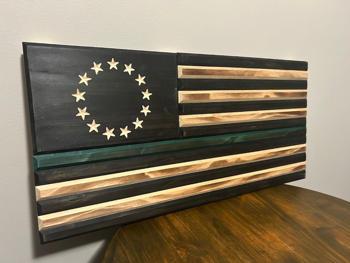 Wooden flag with black field and stars, green line, and alternating stained wood stripes.