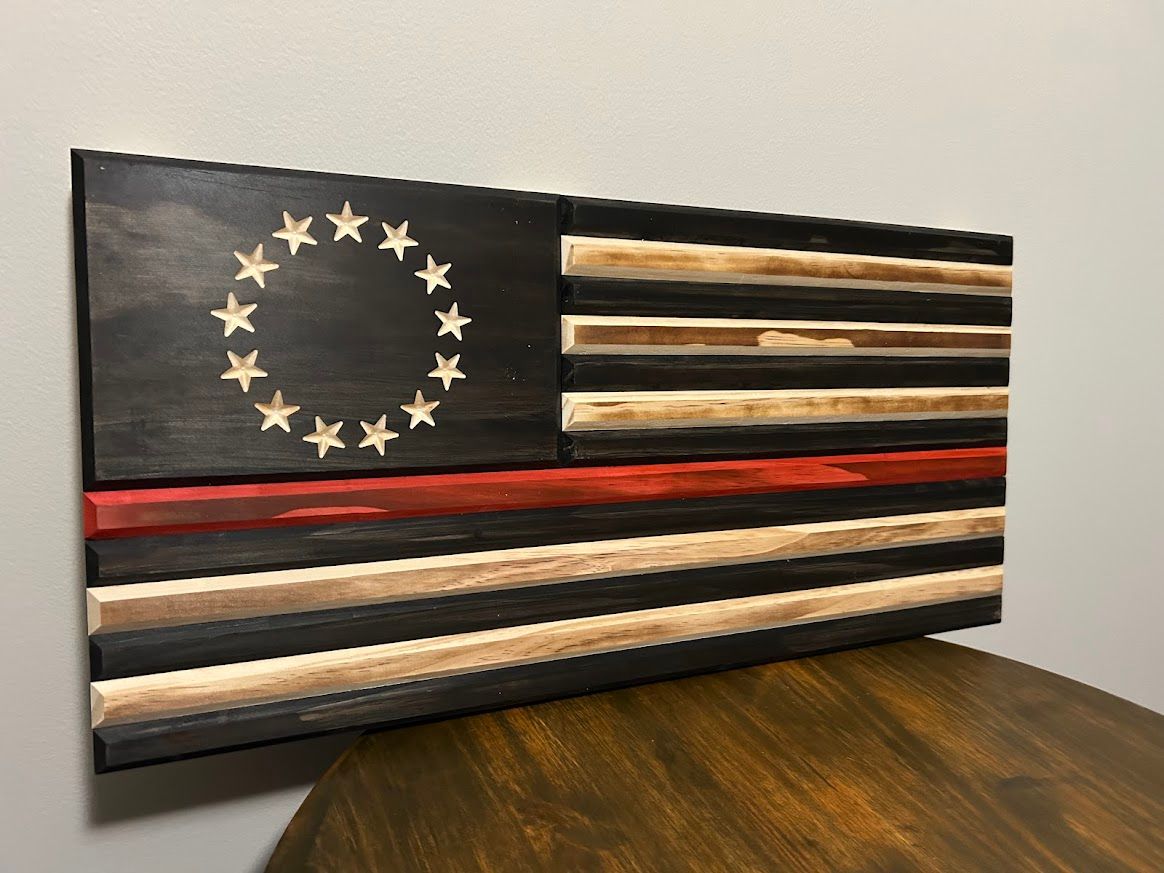 Wooden American flag with black, tan, and red stripes, and white stars in a circle.