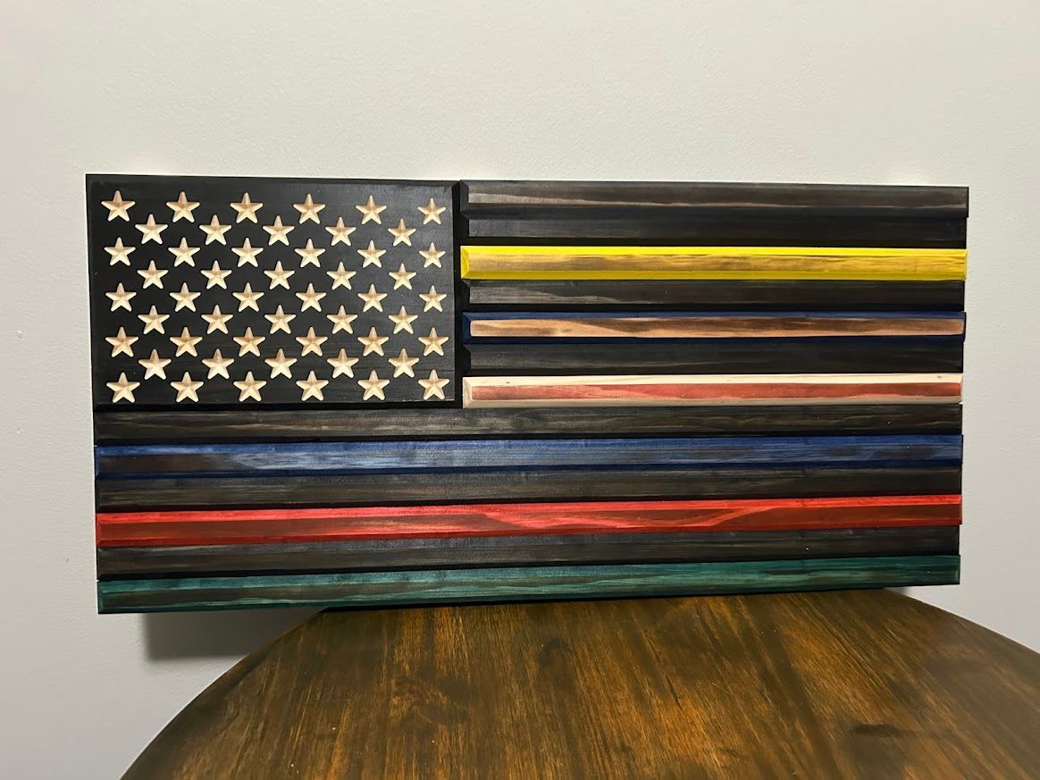 Wooden American flag with carved stars, black, yellow, blue, red, green stripes.