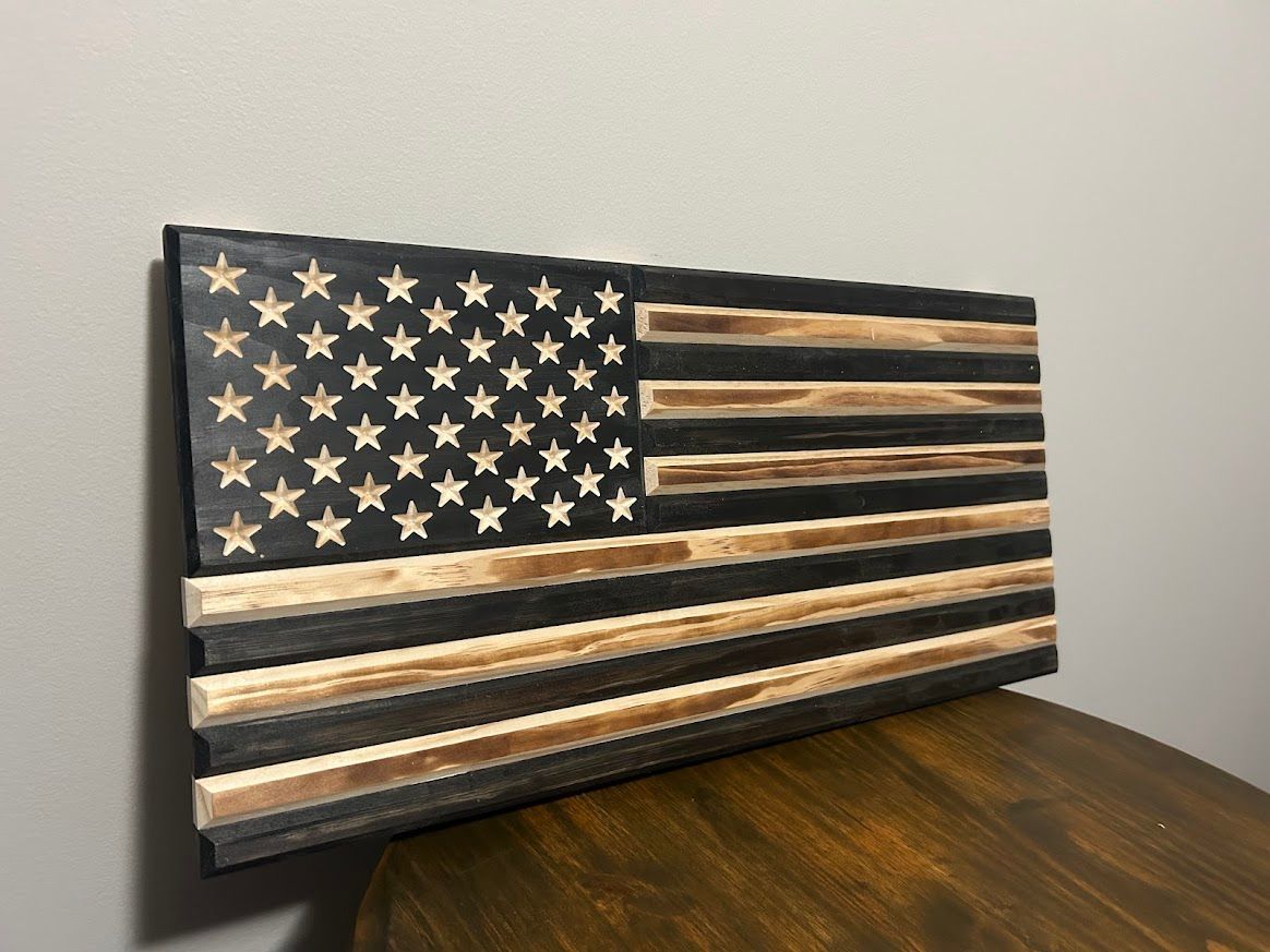 Wooden American flag with charred black and natural wood stripes, star field.