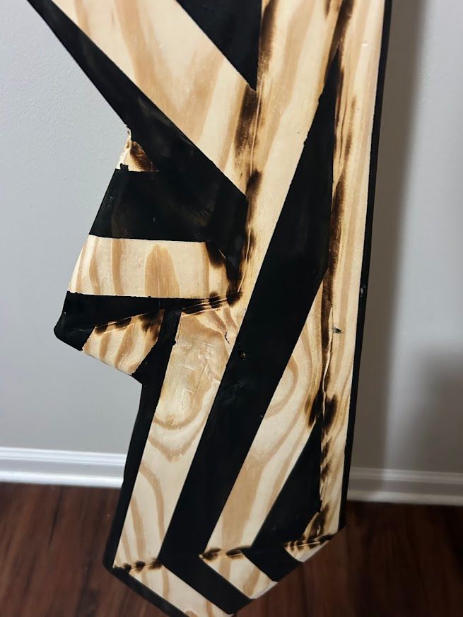 Wooden art piece with black and light wood chevron pattern.