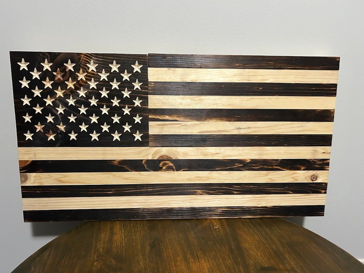 Wooden American flag with charred stripes and star-filled canton.