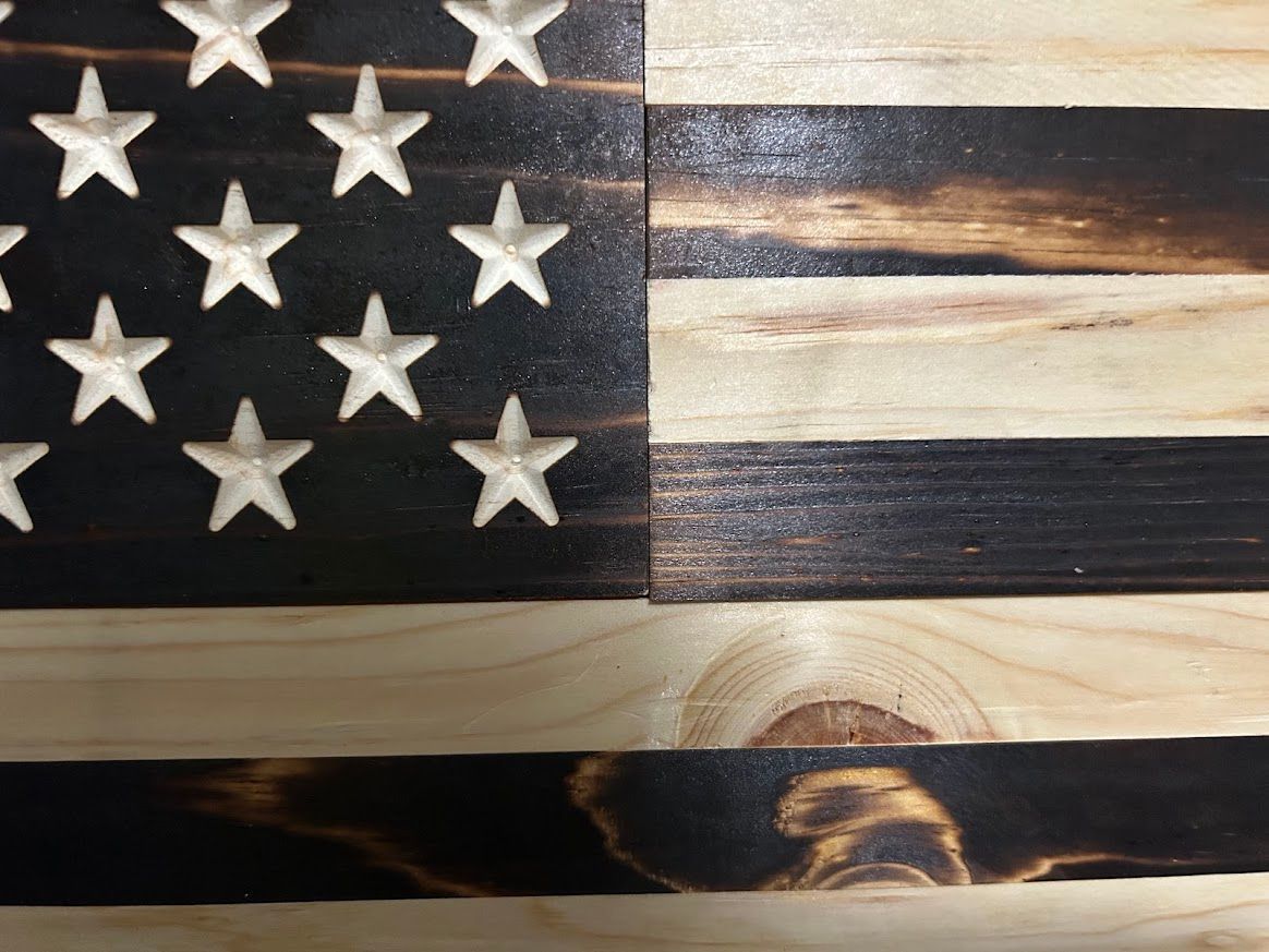 Wooden American flag with charred stripes and star-filled canton.