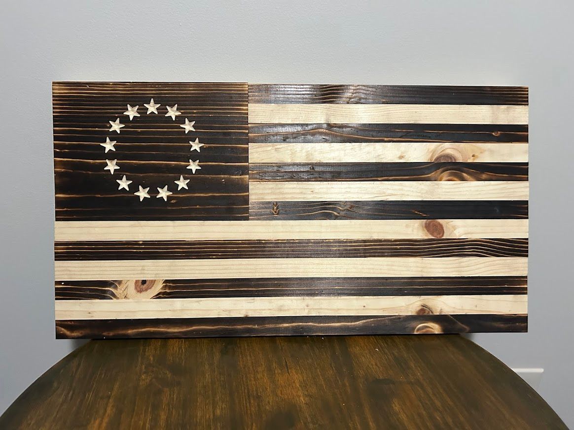 Wooden Betsy Ross flag, burnt black and natural stripes, with a circle of white stars.