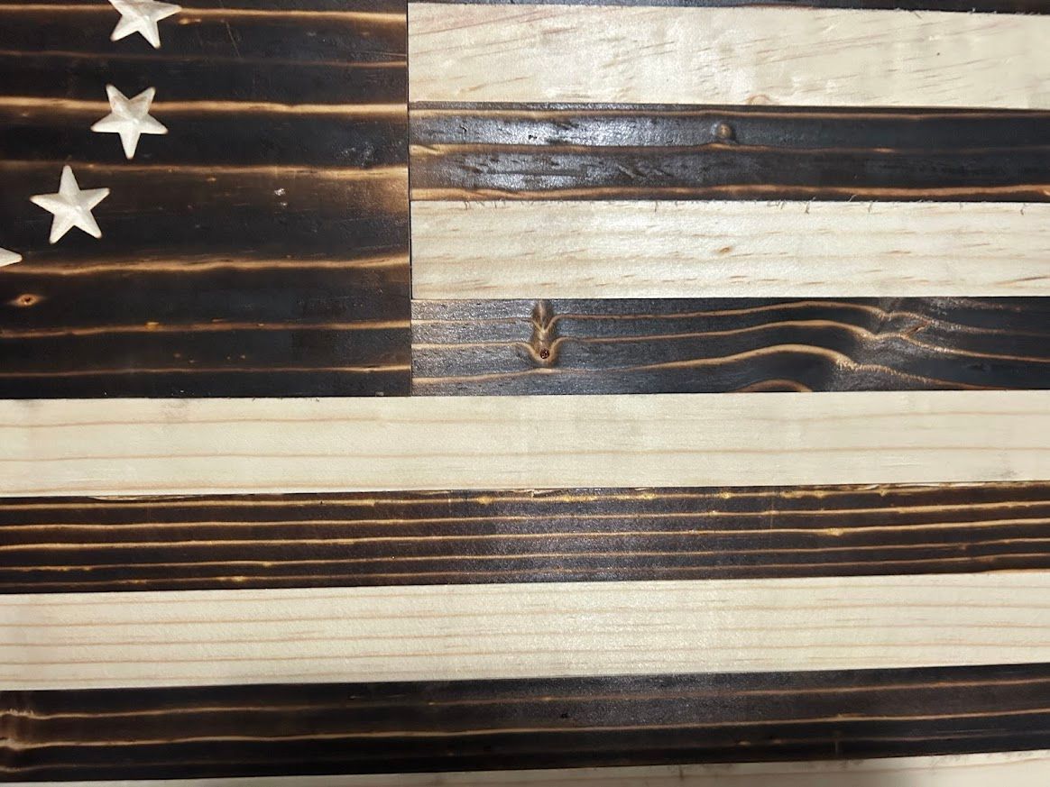 Wooden Betsy Ross flag, burnt black and natural stripes, with a circle of white stars.