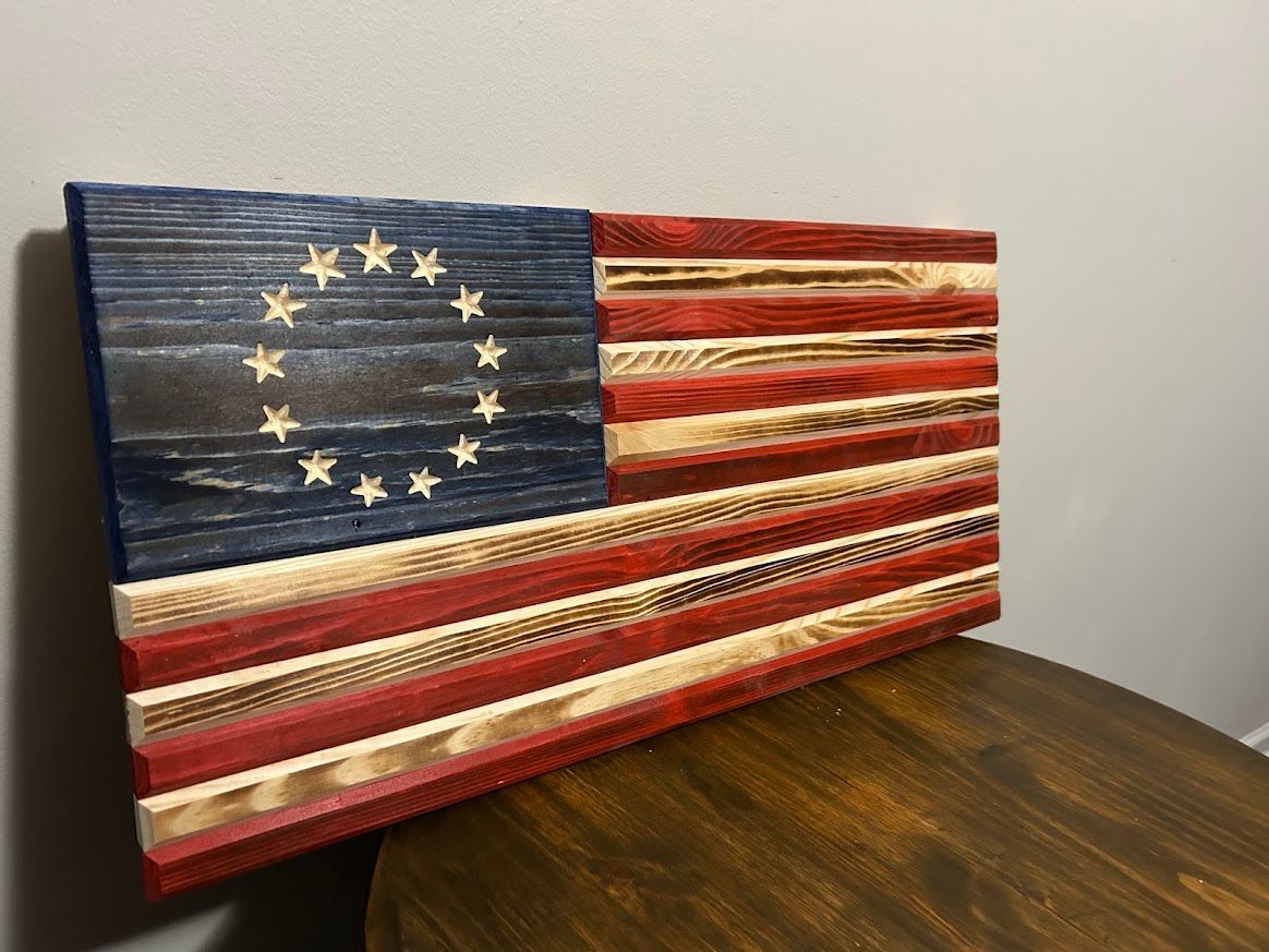 Wooden American flag with 13 stars in blue field and red/natural wood stripes.