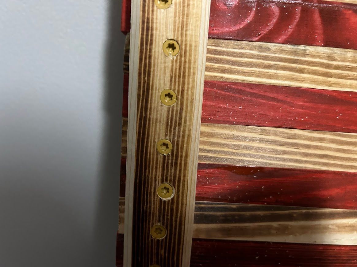 Wooden American flag with red and natural wood stripes, held together with screws.