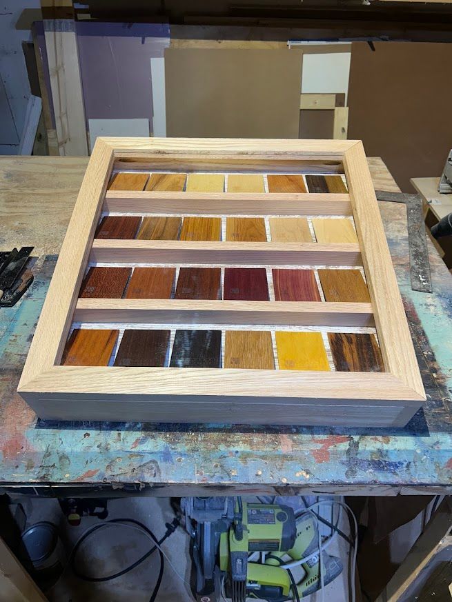 Wooden display case with stained wood samples arranged in rows.