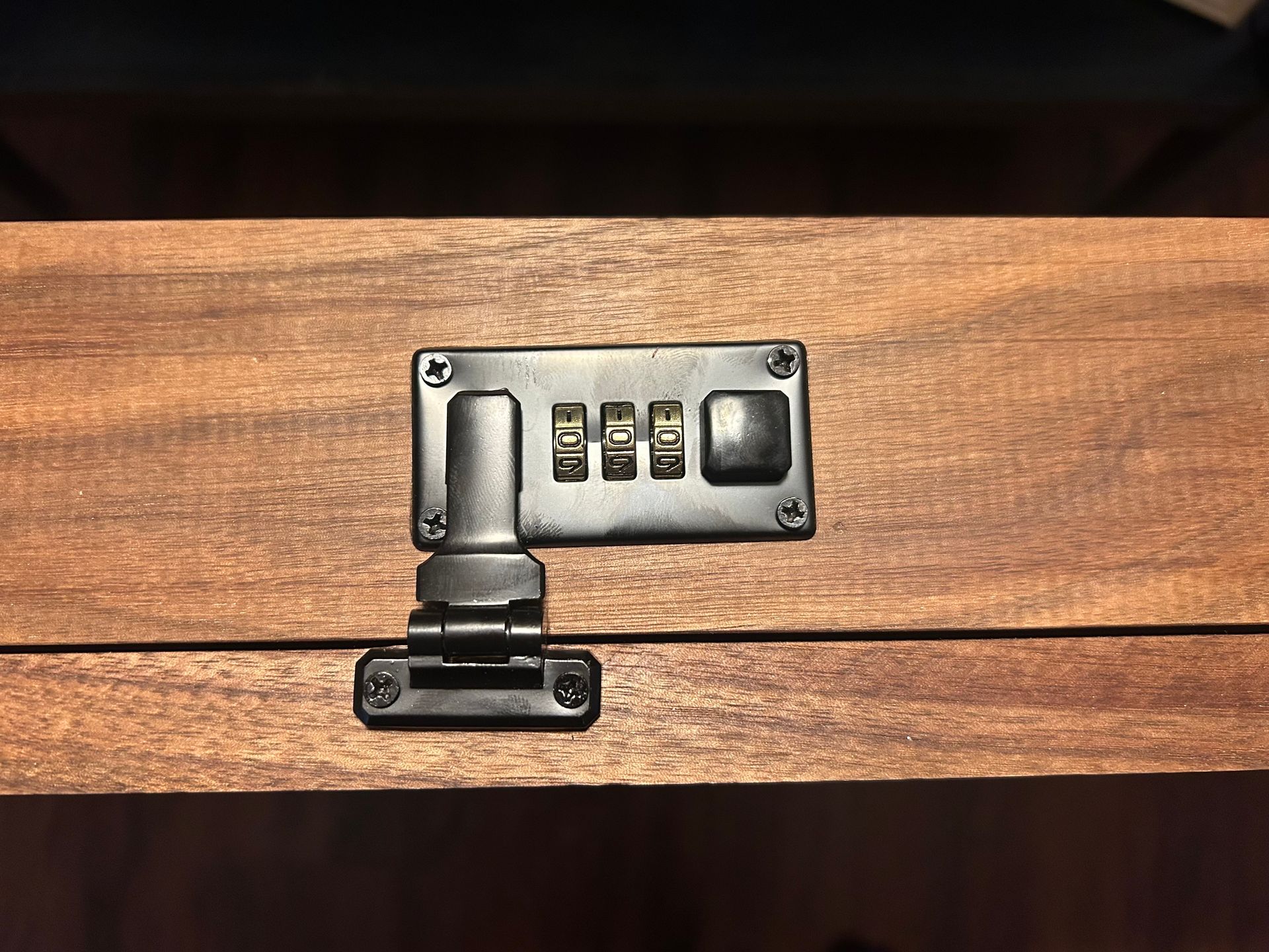 Wooden box with black combination lock and hinge.