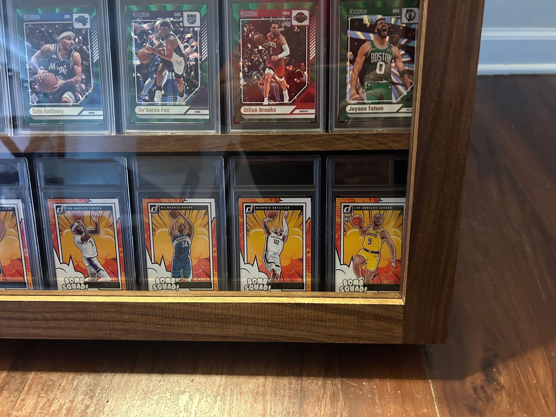 Basketball cards displayed in a wooden case. Some cards are graded.