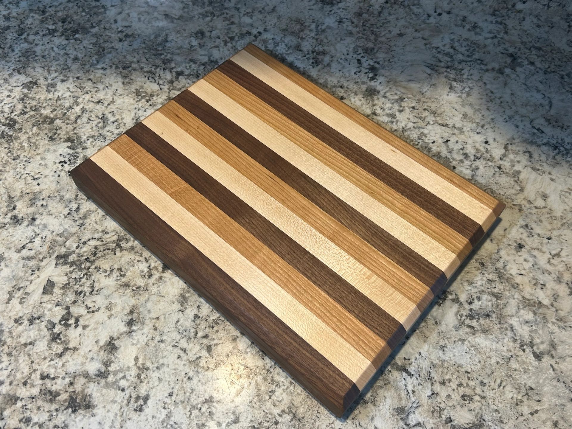 Striped wooden cutting board on a speckled countertop. Brown, tan, and light wood tones.
