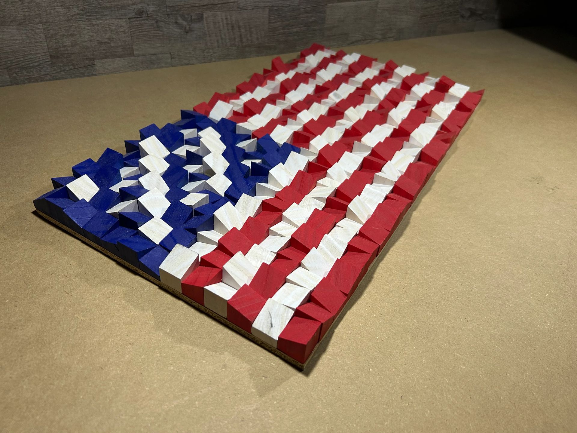 Wooden American flag made of red, white, and blue blocks against a neutral wall.