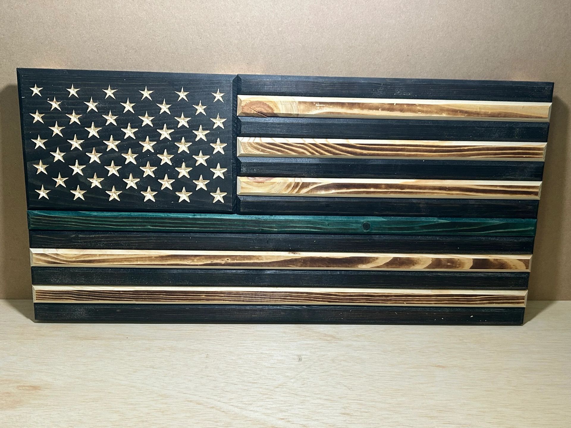 Wooden American flag with a green line, black stripes, and carved stars.