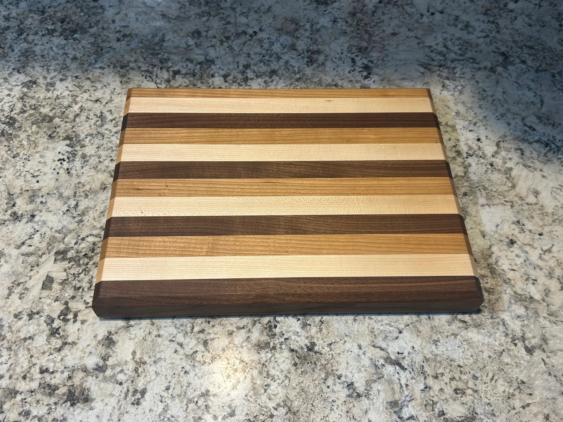 Striped wooden cutting board on a speckled countertop. Brown, tan, and light wood tones.