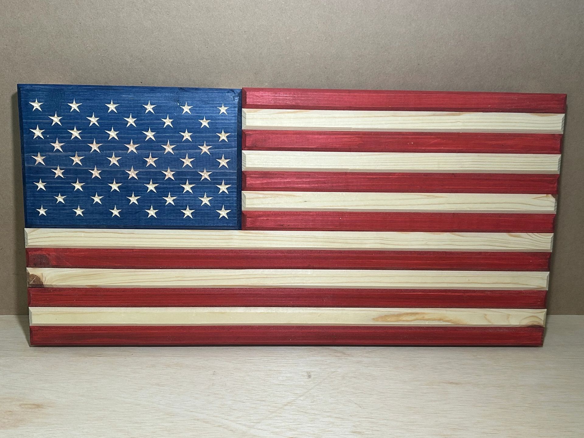 Wooden American flag art piece with painted stars and stripes.
