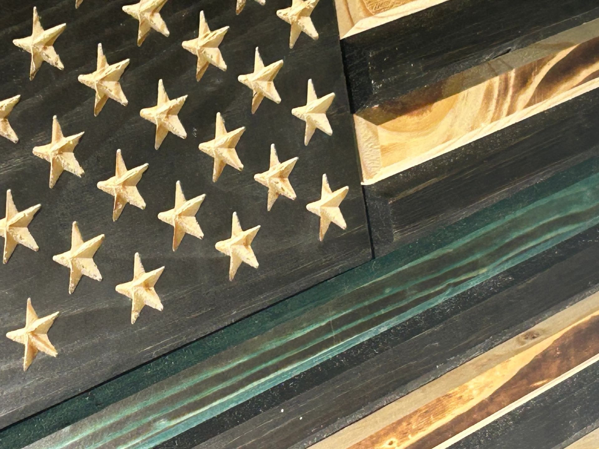 Wooden American flag with a green line, black stripes, and carved stars.