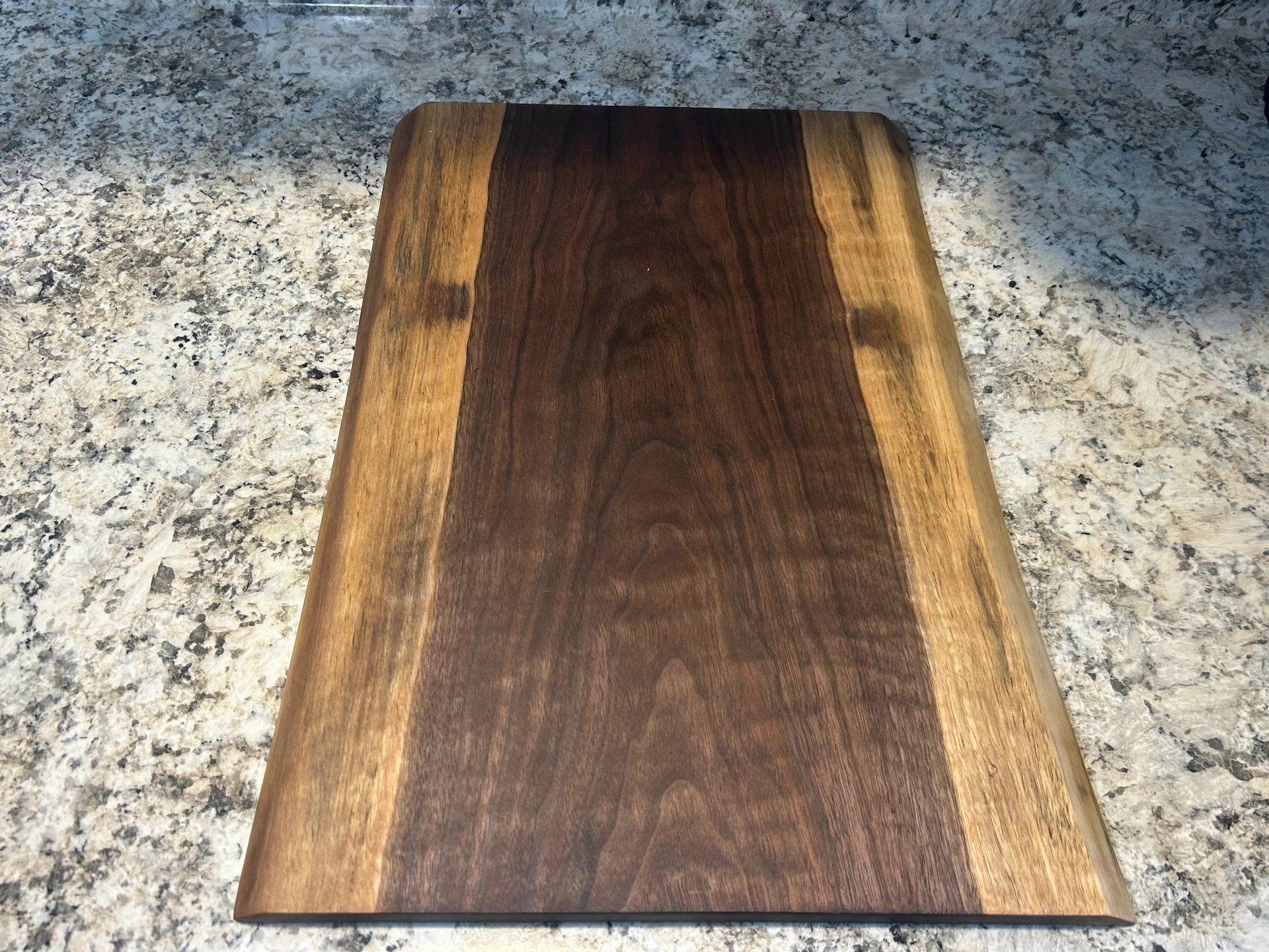 Wooden cutting board with dark brown center and lighter wood sides.