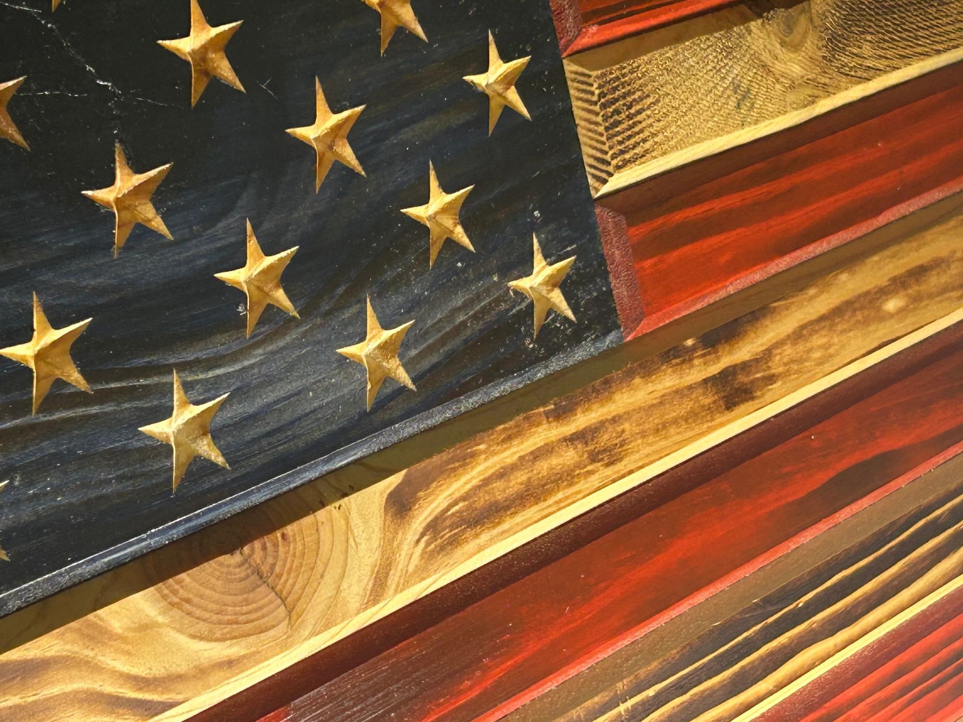 Wooden American flag art with carved stars, blue field, and red/gold stripes.
