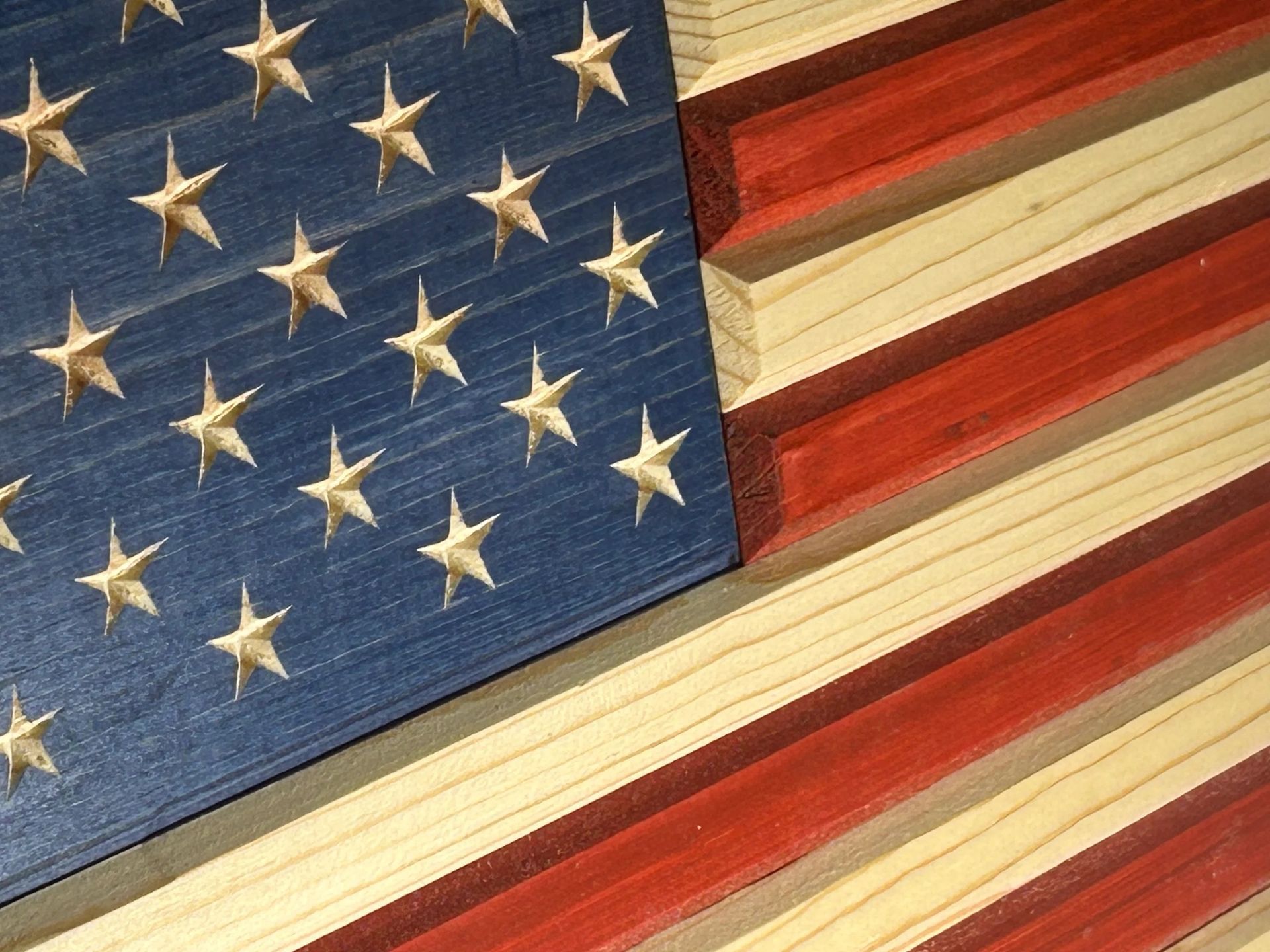 Wooden American flag art piece with painted stars and stripes.