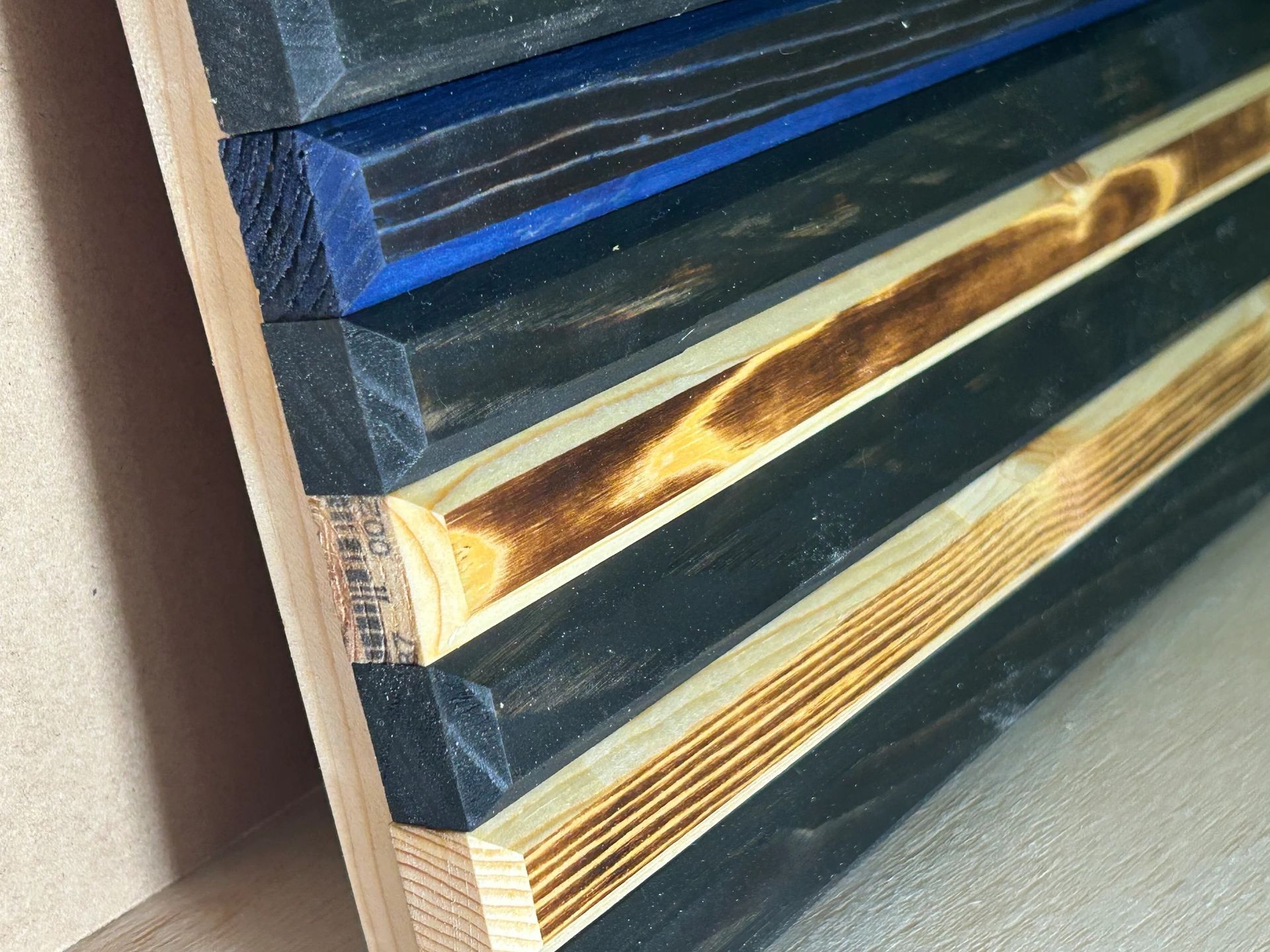 Wooden flag with black, blue, and tan stripes.