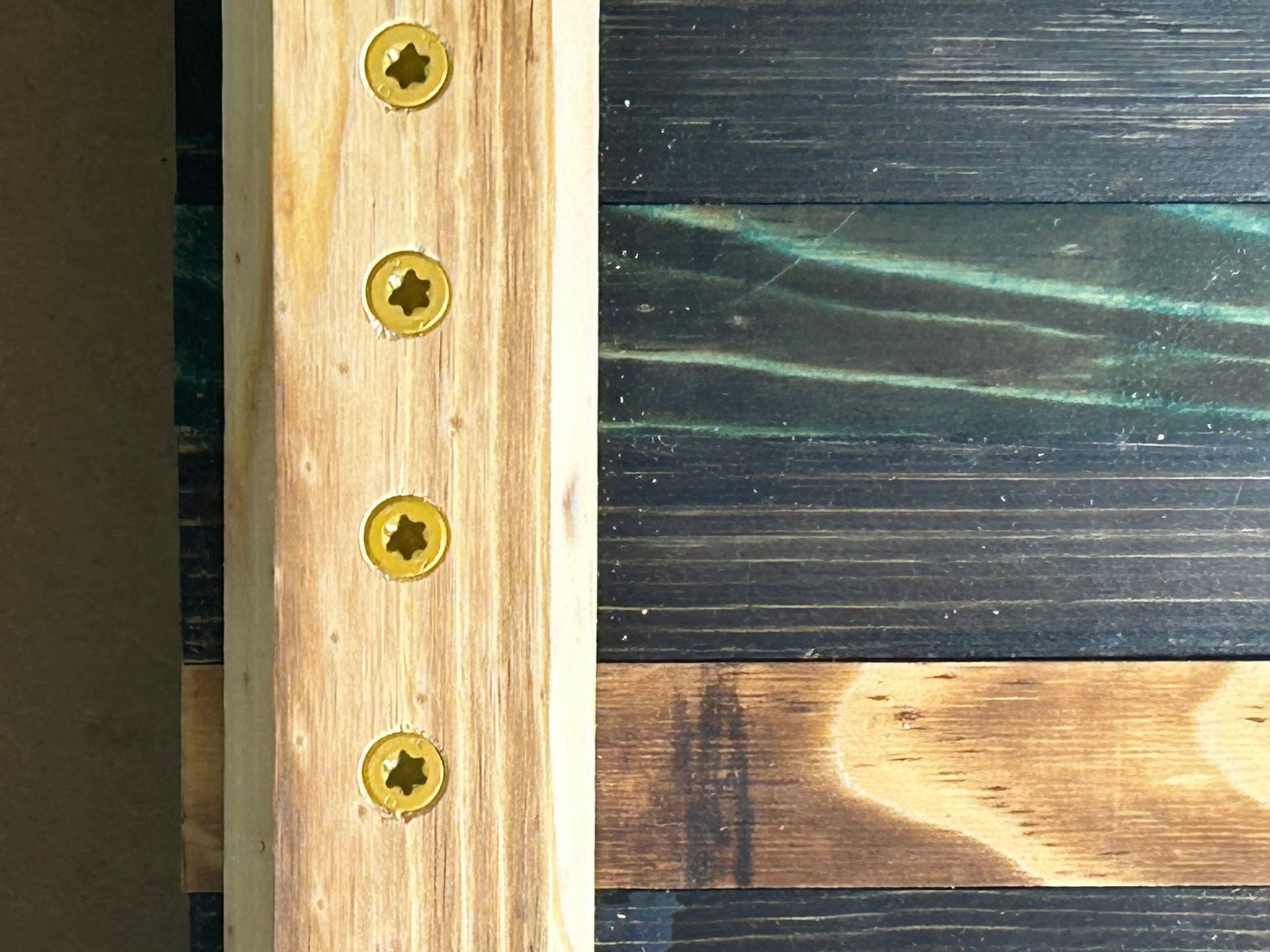 Wooden frame with screws attached to a colorful wooden panel.