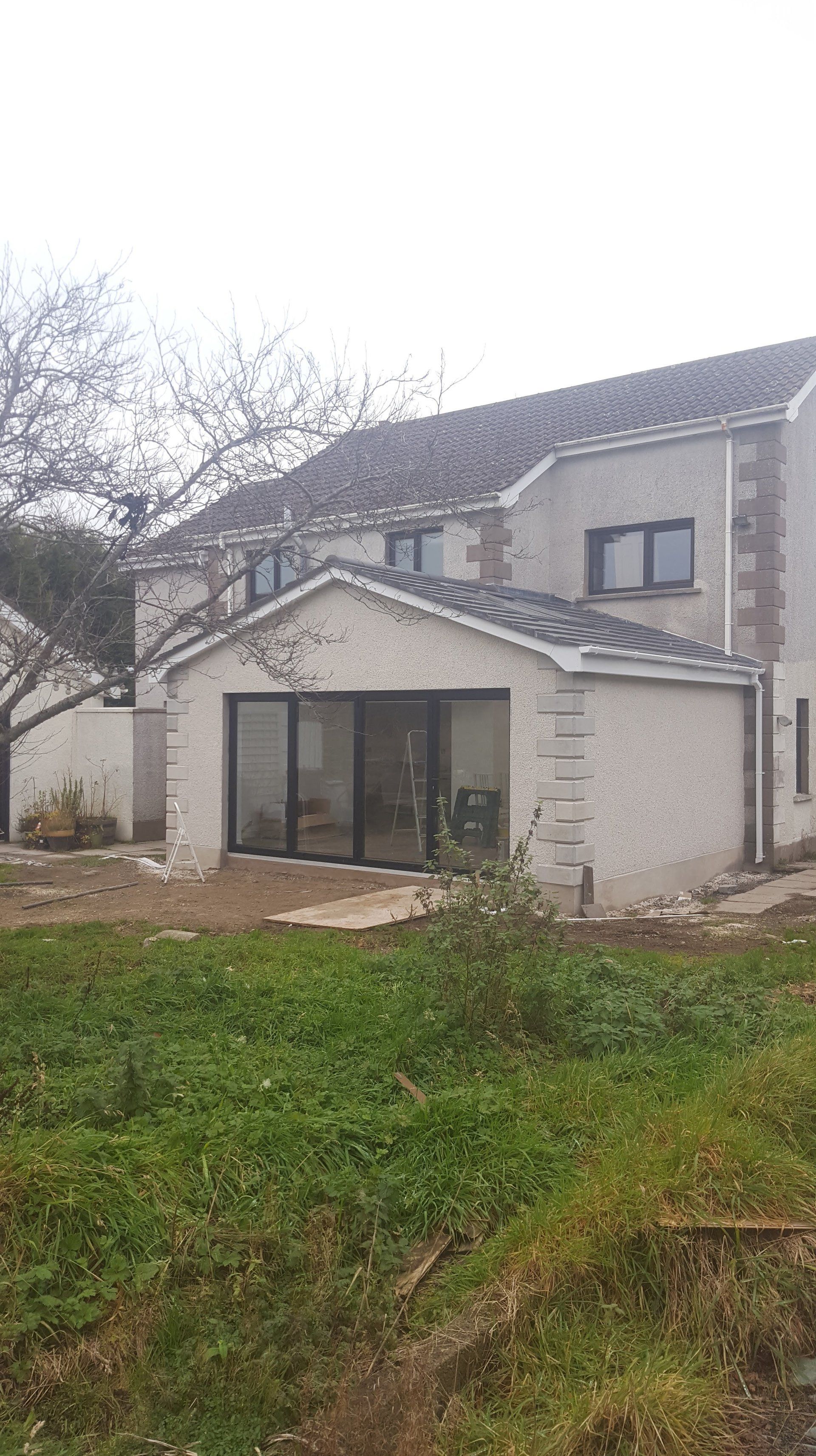 Two-story house with an extension. Extension has sliding glass doors. Overcast day.