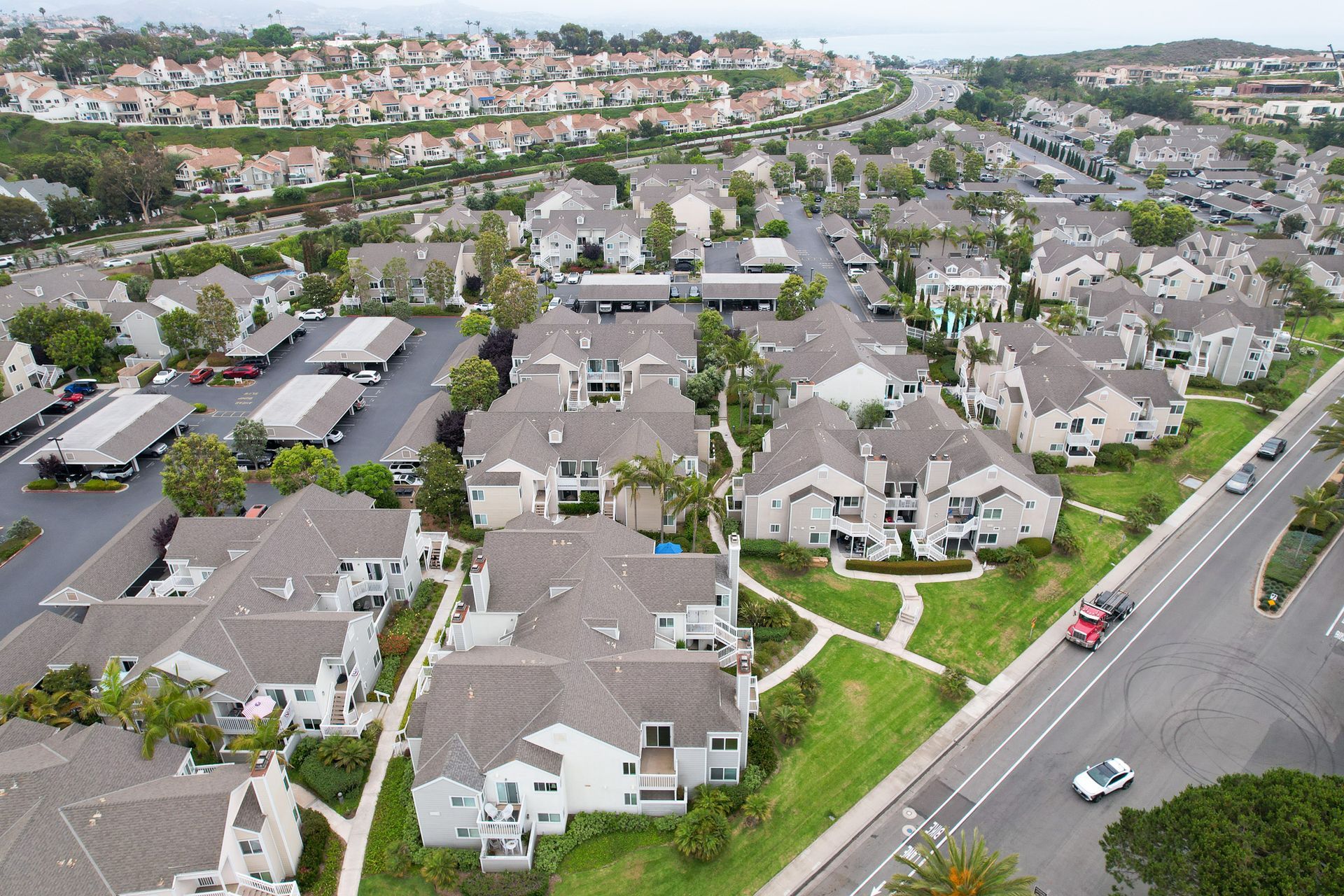 Aerial view of a suburban neighborhood with multiple apartment buildings, green lawns, and a road.