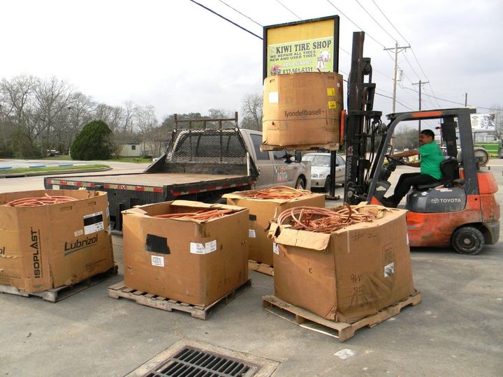 A person in a black coat and red scarf walks through a snow-covered park, holding a red umbrella.
