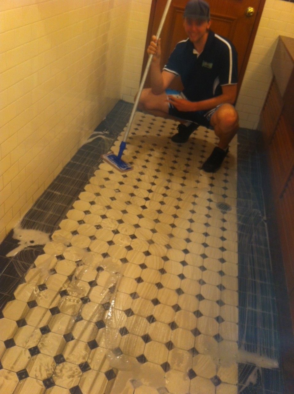 Man cleaning a tiled floor with a mop — Enviro Clean Carpet and Tile Cleaning in Budgewoi, NSW