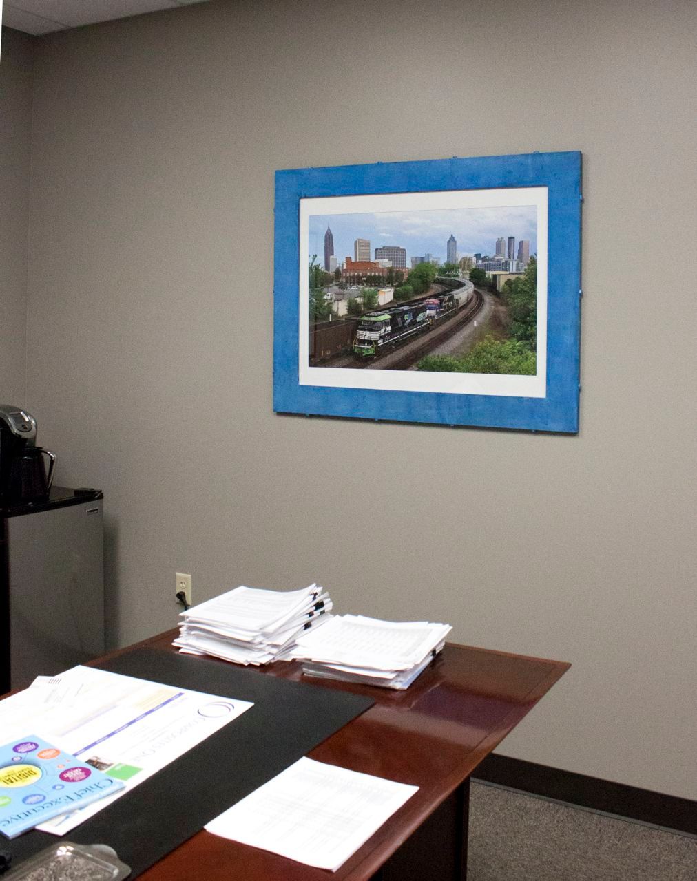 A picture of a train is hanging on the wall above a desk