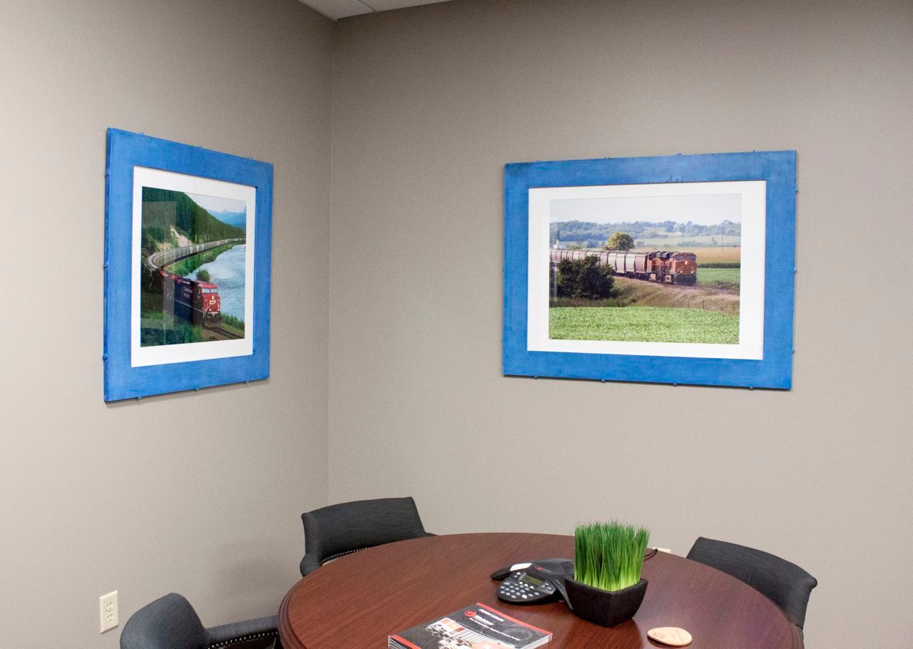 A conference room with a round table and two pictures on the wall.