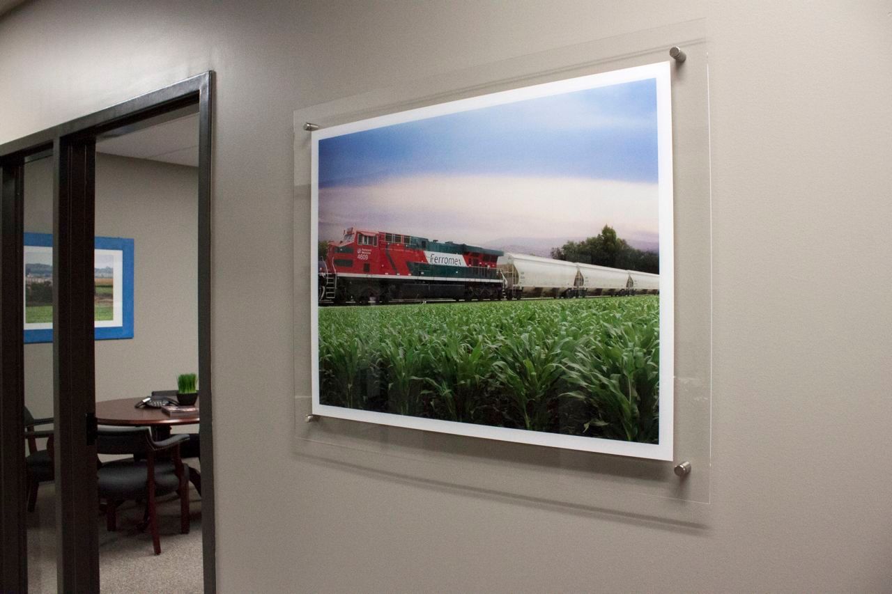 A picture of a train going through a field is hanging on a wall.