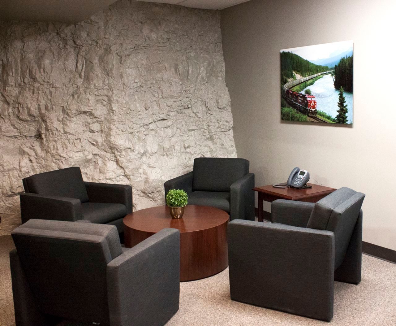 A room with chairs , a table and a painting on the wall.