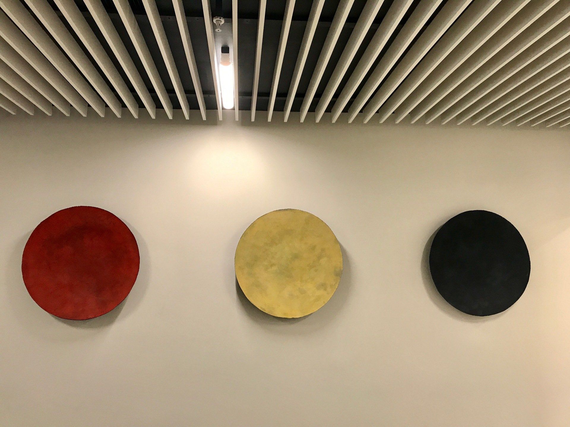 Three circles of different colors are hanging on a wall.