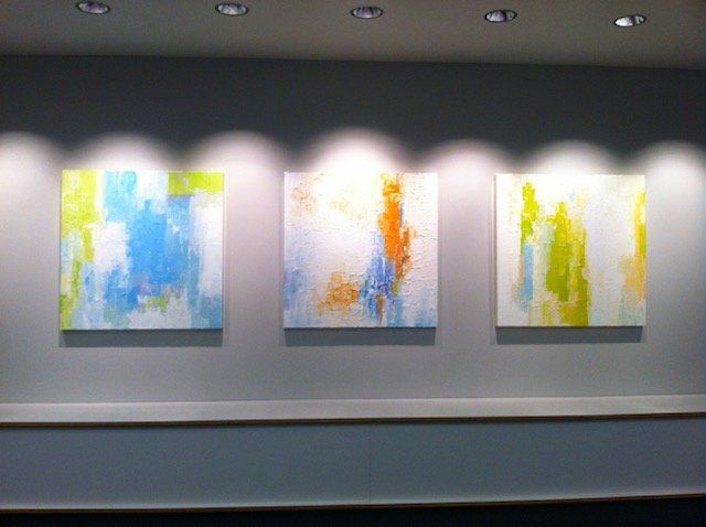 Three colorful paintings are hanging on a wall