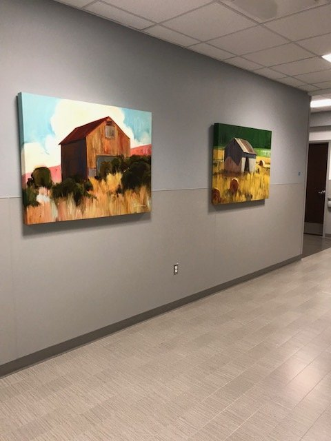 Two paintings are hanging on a wall in a hallway