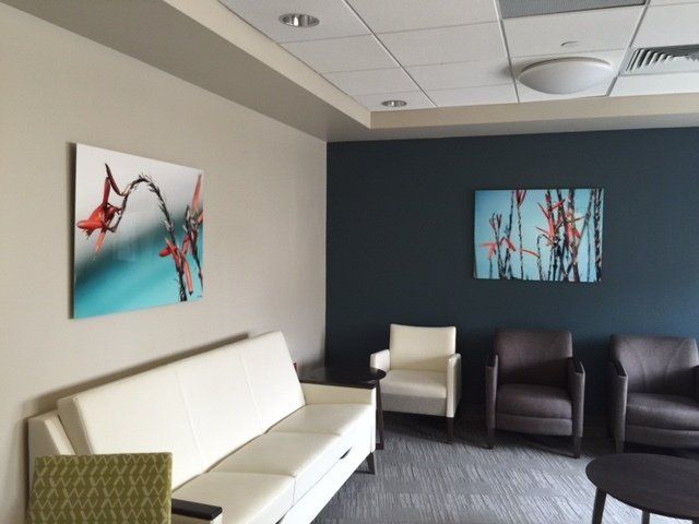 A waiting room with a couch and chairs and two paintings on the wall