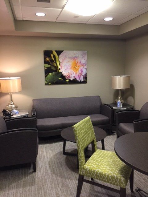A living room with a couch and chairs and a picture of a flower on the wall