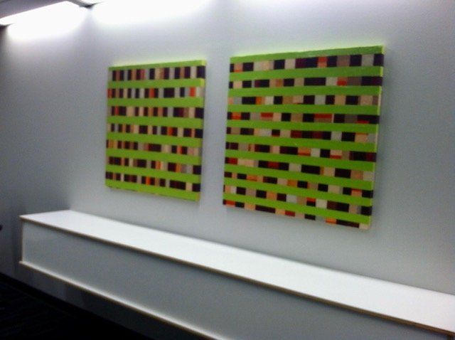 Two green paintings are hanging on a white wall