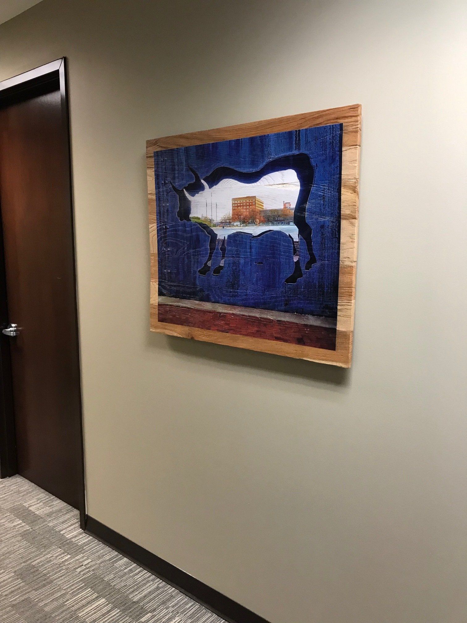 A painting of a cow is hanging on a wall in a hallway.