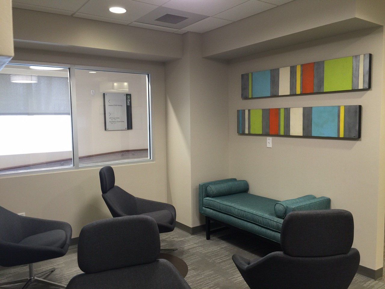 A room with chairs and a bench and paintings on the wall