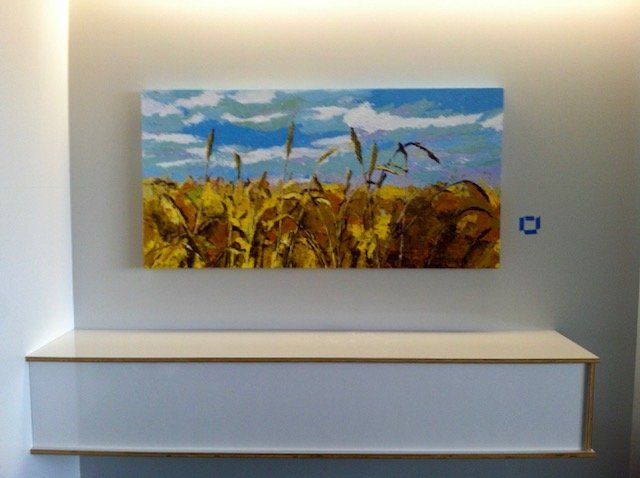 A painting of a field of wheat is hanging on a wall
