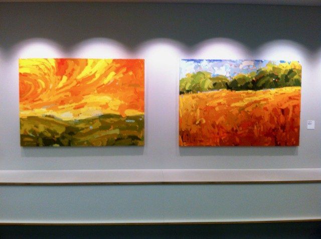 Two paintings are hanging on a wall in a room.