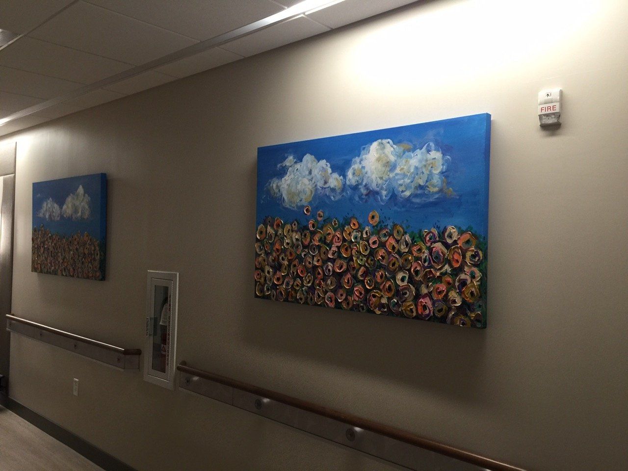 Two paintings are hanging on a wall in a hallway.