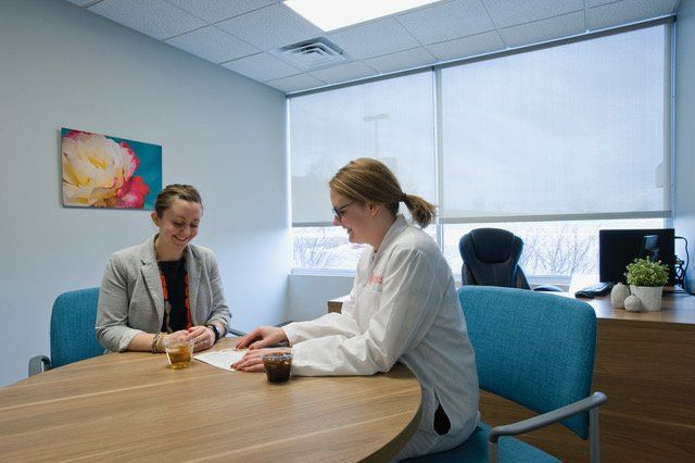 Two women are sitting at a table talking to each other.