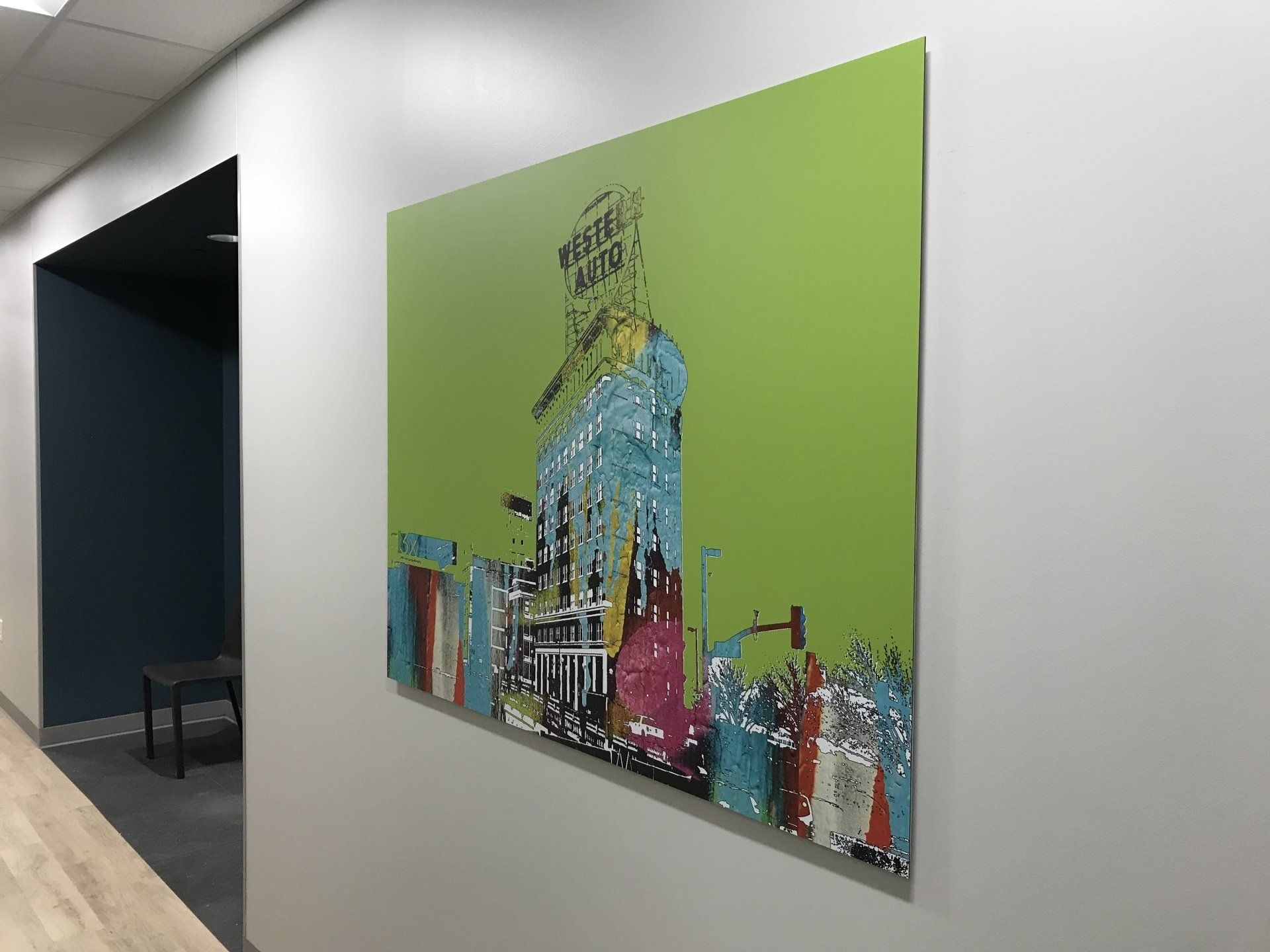 A large green painting is hanging on a wall in a hallway.